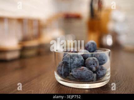 Fresh plums in glass bowl on wooden table Stock Photo