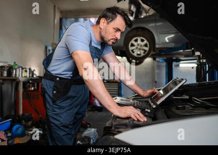 Car mechanic using diagnostic software on a laptop in a garage Stock Photo