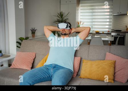 Man relaxing at home wearing virtual reality headset Stock Photo