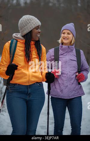 Diverse women friends enjoying winter hiking and talking Stock Photo