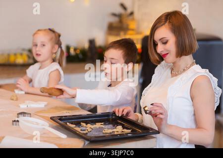 Happy family  mom and two kids make Christmas cookies and have fun together at home in the kitchen.  Children siblings making ho Stock Photo