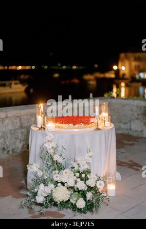 Romantic seaside celebration. Elegant vow ceremony on coastal stone terrace with flowers and candles Stock Photo