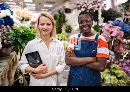 Two smiling florists posing in their flower shop Stock Photo