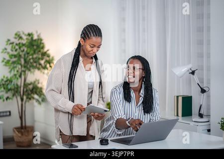 Two Black women collaborating on business project in office Stock Photo