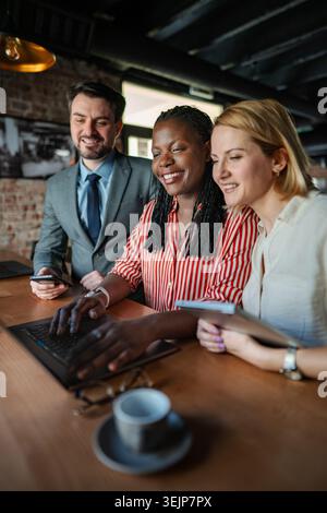 Diverse business team collaborating using laptop and tablet Stock Photo