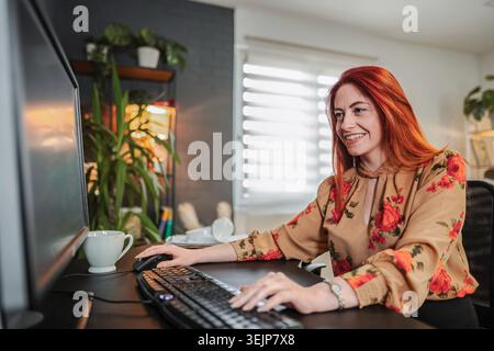 Young woman working from home typing on a desktop computer keyboard Stock Photo