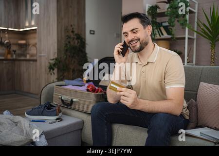 Man booking a trip using his smartphone and credit card Stock Photo