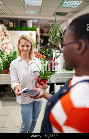 Woman paying with contactless smartphone in a flower shop Stock Photo