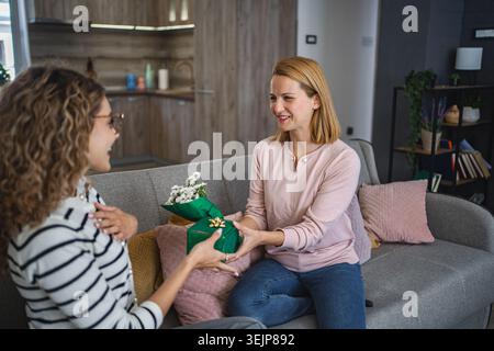 Two friends Sitting on a Couch Exchanging a Present Stock Photo
