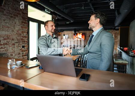 Businessmen shaking hands making partnership agreement in cafe Stock Photo