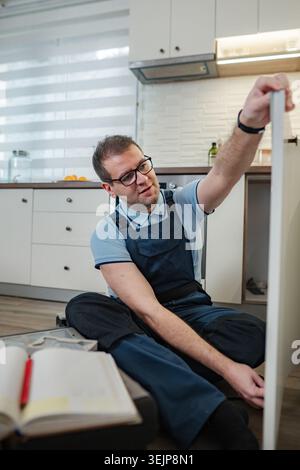 Handyman assembling kitchen cabinet in modern home kitchen Stock Photo