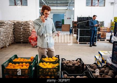 Warehouse workers managing inventory and fresh produce using technology Stock Photo