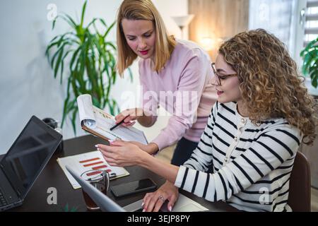 Two female colleagues working together on business report Stock Photo