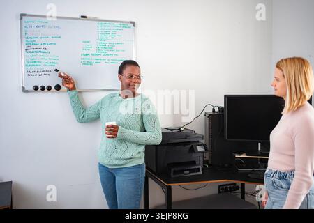 Businesswomen discussing project ideas on whiteboard in office Stock Photo