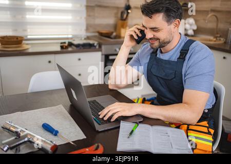 Plumber working on laptop and talking on the phone Stock Photo