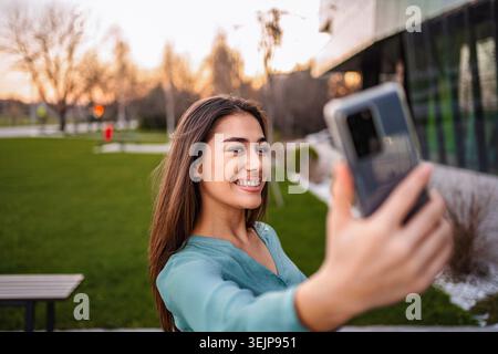 Young woman taking a selfie with smartphone in a park Stock Photo