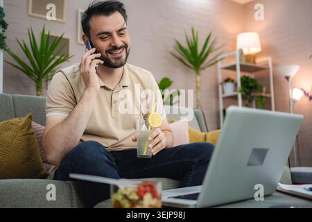 Freelancer enjoying a refreshing drink while working from home Stock Photo