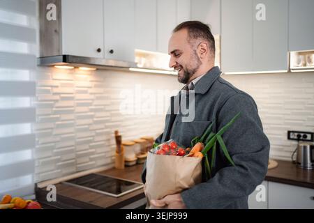 Happy man holding paper grocery bag with fresh vegetables Stock Photo