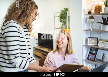 Two smiling female colleagues working on a business report Stock Photo