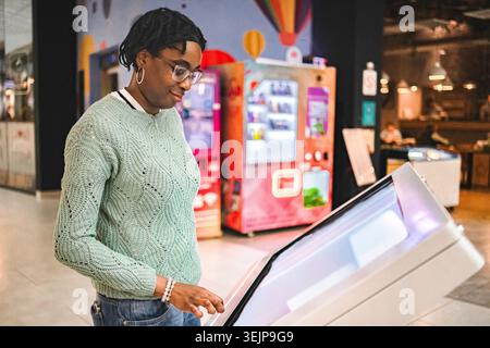 Woman using interactive digital kiosk for information display Stock Photo