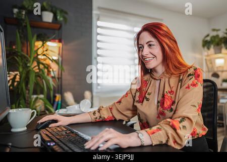 Smiling businesswoman working from home using desktop computer Stock Photo
