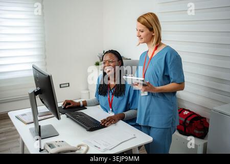 Diverse nurses collaborating on computer and digital tablet Stock Photo