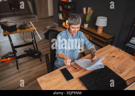 Architect reviewing blueprints in her home office during renovation works Stock Photo