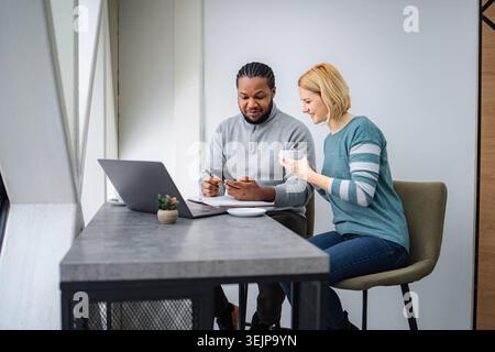 Diverse colleagues collaborating using technology in modern office space Stock Photo
