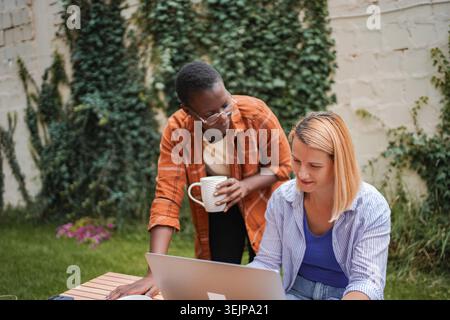 Two businesswomen collaborating on a project in a garden Stock Photo