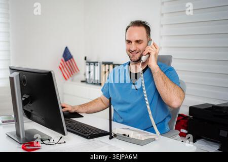 Male nurse talking on phone and using computer Stock Photo