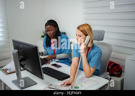 Medical team collaborating in office talking on telephone and using computer Stock Photo