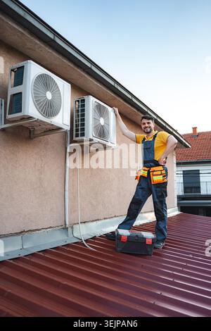 HVAC technician checking air conditioning units on a roof Stock Photo