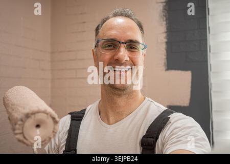 Selfie of Man Smiling While Holding a Paint Roller. Stock Photo