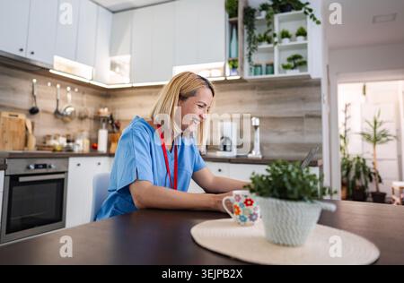 Female doctor working from home, using laptop and smiling Stock Photo