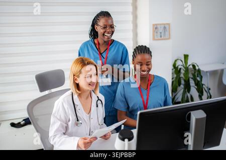 Diverse medical team collaborating on computer in clinic Stock Photo
