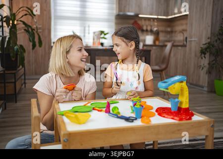 Daughter and mother play together with plasticine modeling Stock Photo