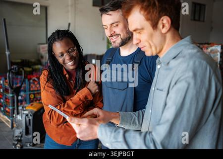 Diverse team collaborating on digital tablet in warehouse Stock Photo