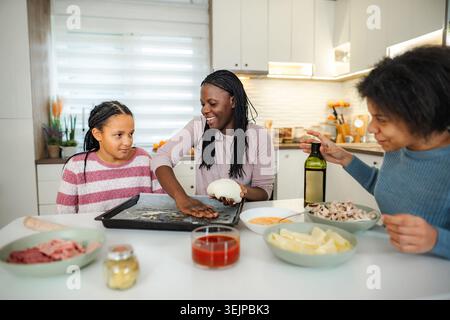 Family making pizza together in modern kitchen at home Stock Photo