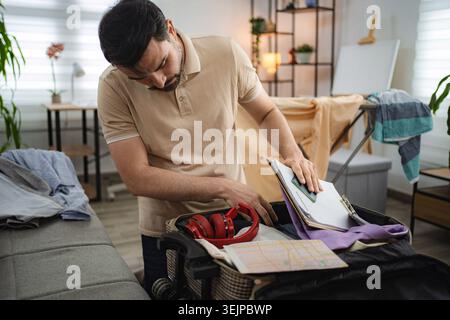 Man packing suitcase for business trip at home. Stock Photo