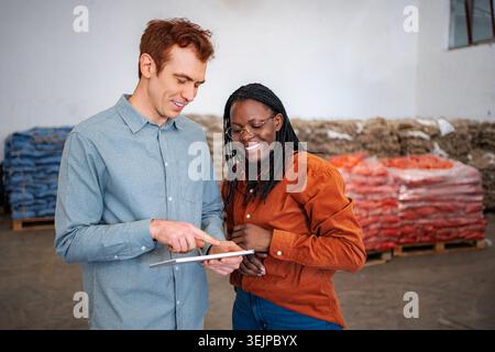 Warehouse workers collaborating on inventory management using digital tablet Stock Photo