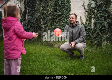 Father playing catch with daughter in backyard Stock Photo