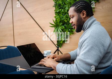 African American man typing on laptop in cafe Stock Photo