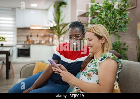 Joyful friends sharing a laugh while enjoying a cozy evening indoors Stock Photo