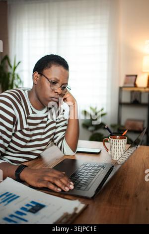 Young adult woman feeling bored working on laptop at home Stock Photo