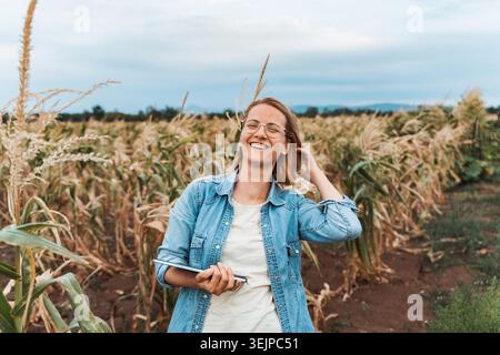 Farmer smiling and holding tablet in corn field Stock Photo