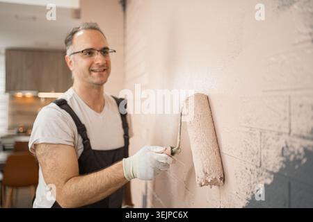 Man Painting Wall With Paint Roller Stock Photo