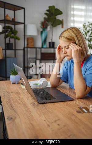 Stressed doctor having headache while working from home Stock Photo