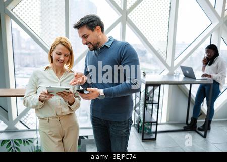 Business colleagues discussing data on digital tablet and smartphone in modern office Stock Photo