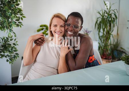 Two smiling friends hugging each other at home Stock Photo