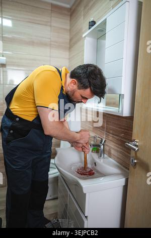 Plumber using plunger in bathroom sink Stock Photo